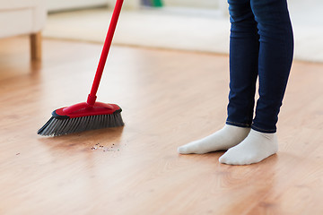 Image showing close up of woman legs with broom sweeping floor