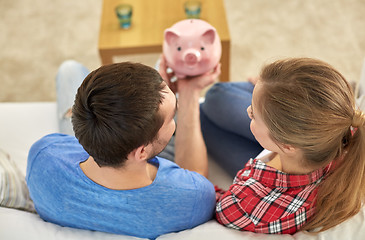 Image showing close up of couple with piggy bank sitting on sofa