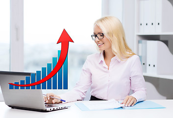 Image showing smiling businesswoman with laptop and papers