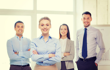 Image showing smiling businesswoman in office with team on back