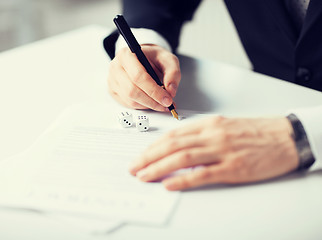 Image showing man hands with gambling dices signing contract