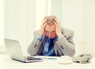 Image showing upset older businessman with laptop and telephone