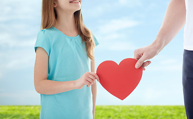 Image showing close up of girl and male hand holding red heart