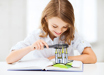 Image showing girl with book looking to castle through magnifier