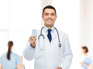 Image showing smiling male doctor in white coat with tablets