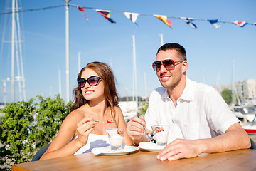 Image showing smiling couple eating dessert at cafe