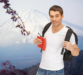 Image showing happy young man with backpack and book travelling