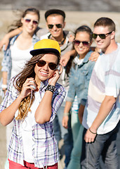 Image showing teenage girl with headphones and friends outside