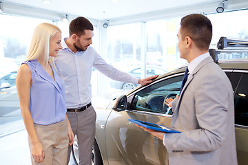 Image showing happy couple with car dealer in auto show or salon