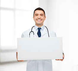 Image showing smiling male doctor holding white blank board