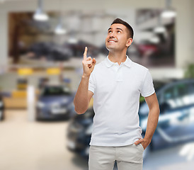 Image showing smiling man pointing finger up over auto show