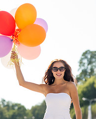 Image showing smiling young woman in sunglasses with balloons