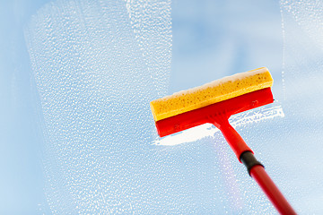 Image showing close up of hand cleaning window with sponge