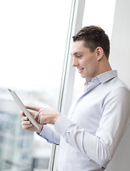 Image showing smiling businessman with tablet pc in office