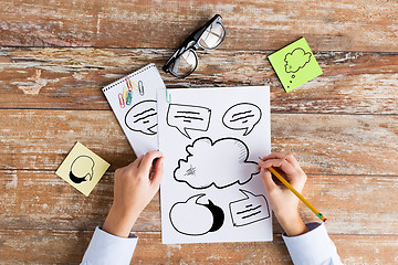 Image showing close up of hands drawing text bubbles in notebook