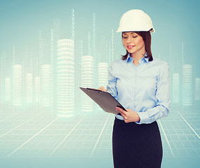 Image showing smiling businesswoman in helmet with clipboard