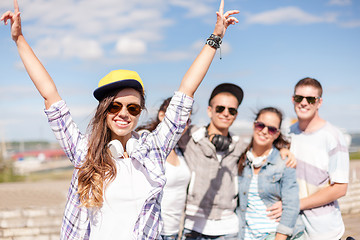 Image showing teenage girl with headphones and friends outside