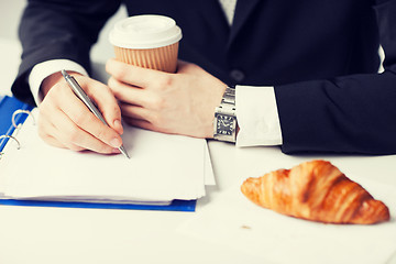 Image showing businessman with coffee writing something