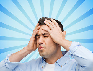 Image showing unhappy man with closed eyes touching his forehead