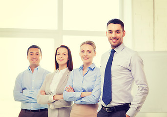 Image showing smiling businessman in office with team on back