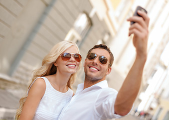 Image showing smiling couple with smartphone in the city