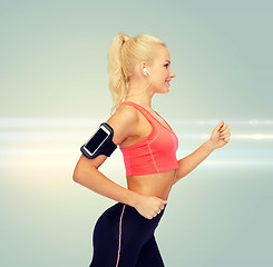 Image showing sporty woman running with smartphone and earphones