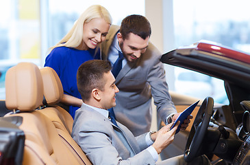 Image showing happy couple with car dealer in auto show or salon