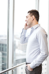 Image showing smiling businessman with smartphone in office