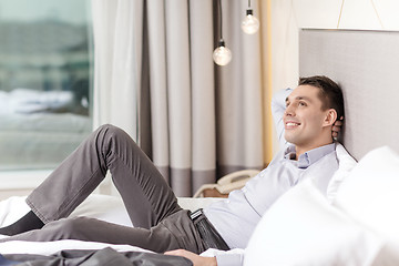 Image showing happy businesswoman lying in bed in hotel room