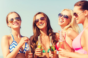 Image showing group of smiling young women drinking on beach