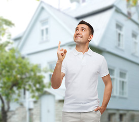 Image showing man pointing finger up over house background