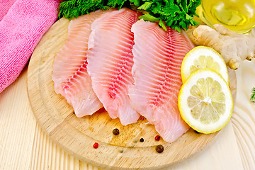 Image showing Tilapia with oil and lemon on board