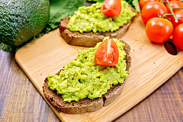 Image showing Sandwich with guacamole avocado and tomato on dark board