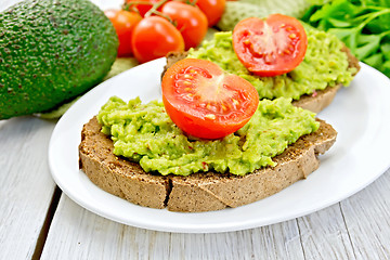 Image showing Sandwich with guacamole avocado and tomato on light board