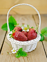 Image showing Strawberries in basket with flowers and leaves on board