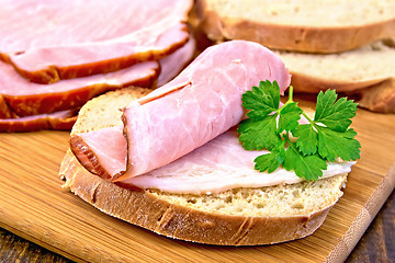 Image showing Sandwich with ham and parsley on board