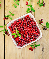 Image showing Lingonberry red with leaves in bowl on board