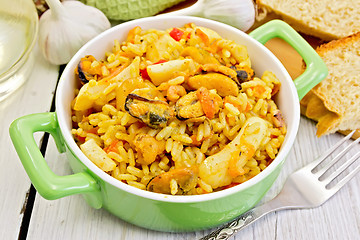 Image showing Pilaf with seafood and fork on board