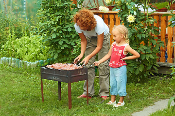 Image showing Little girl helping her mother to cook shish kebab