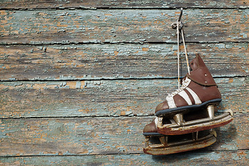 Image showing vintage pair of  ice skates hanging on a cracked paint wall