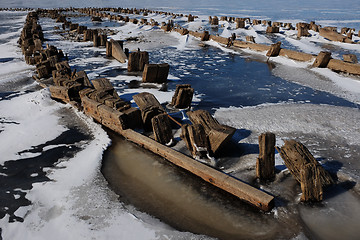 Image showing remains of a wooden pier on the lake in winter