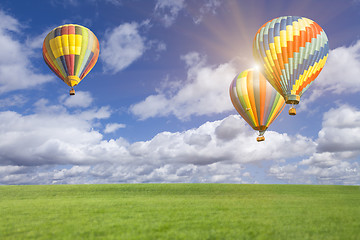 Image showing Hot Air Balloons In Beautiful Blue Sky Above Grass Field 