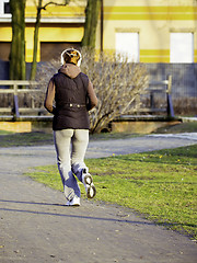 Image showing young woman with headphones jogging in park