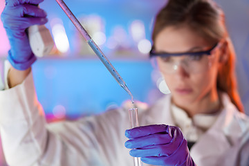 Image showing Attractive young scientist pipetting.