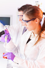 Image showing Young scientist pipetting red solution.