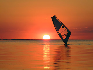 Image showing Silhouette of a windsurfer on waves of a gulf on a sunset 1