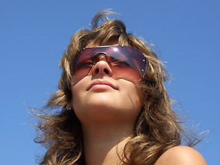 Image showing portrait of the girl in sunglasses on a background of the blue s