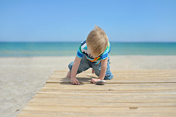 Image showing Small boy playing with stones on the beach