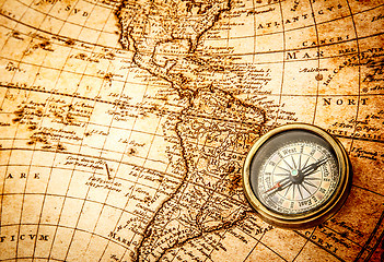 Image showing Vintage compass lies on an ancient world map.