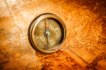 Image showing Vintage compass lies on an ancient world map.